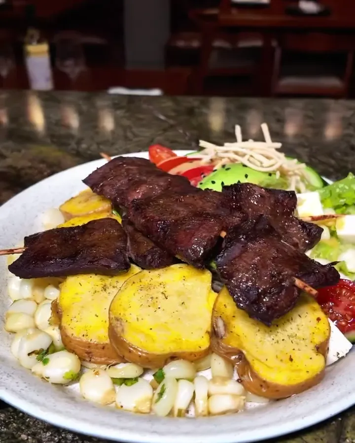 Anticuchos de corazón con papas doradas y choclo