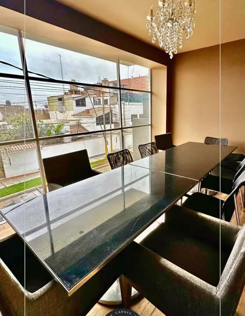 Salón privado con mesa de mármol, ventanal y araña de cristal